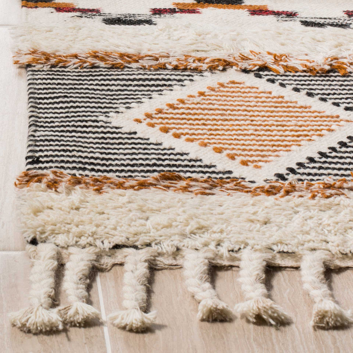 Soft ivory pile, fine black stripes, and an orange diamond meet chunky knotted fringe