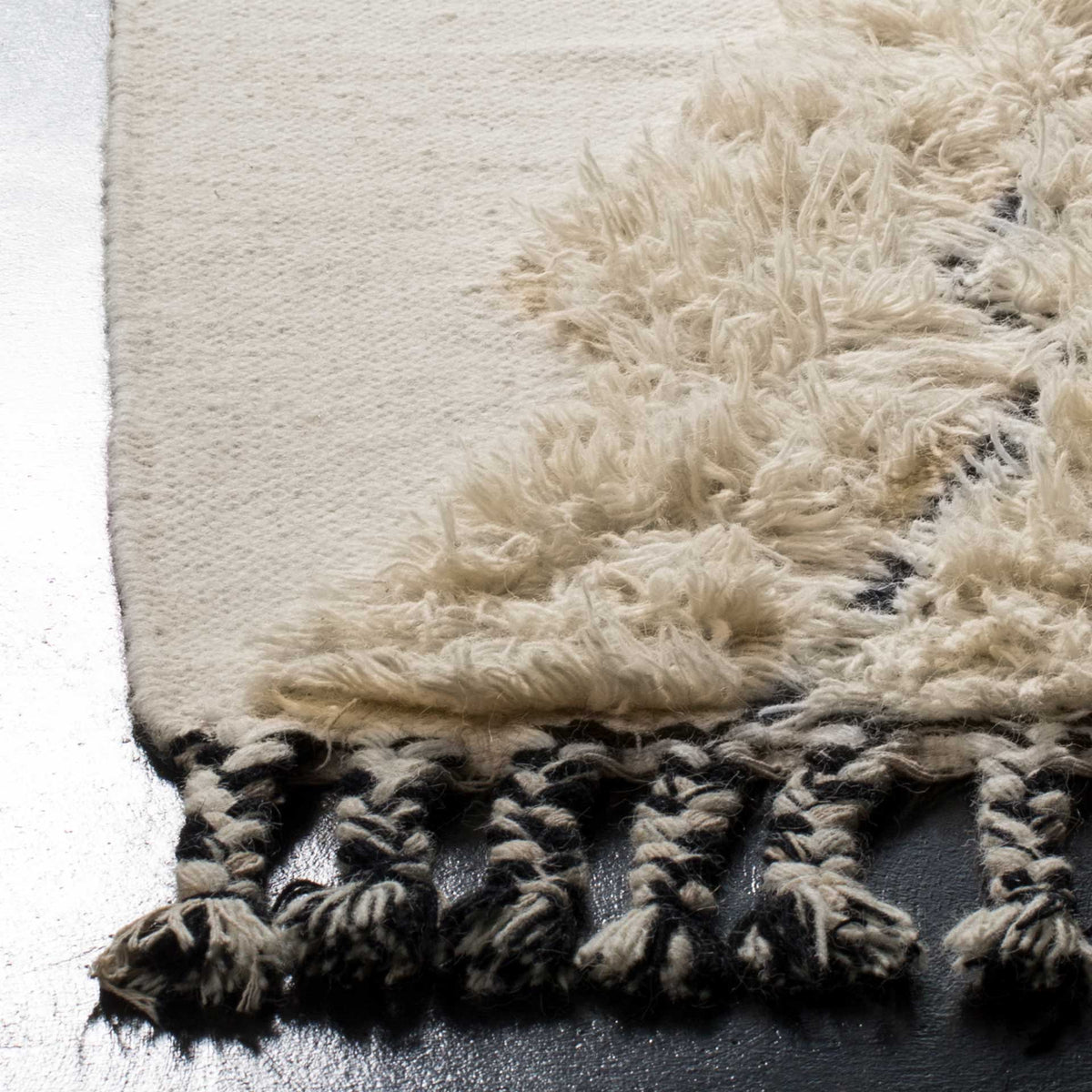Plush ivory pile meets a smooth weave and twisted black-and-ivory fringe
