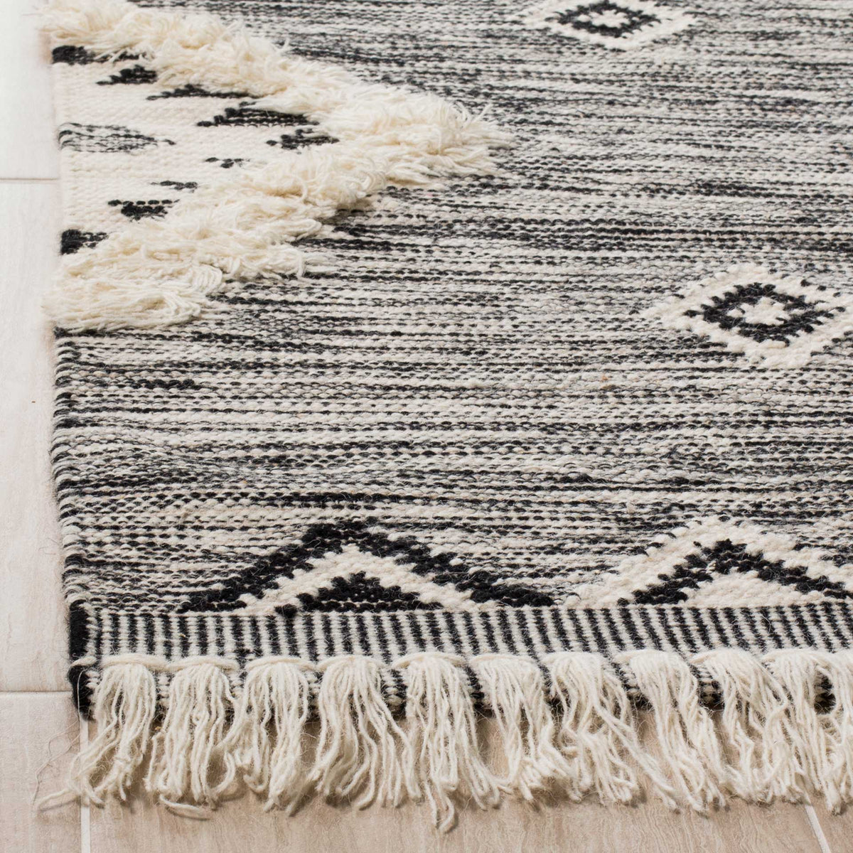 Soft fringe and raised ivory detailing accent the rug's finely striped black and ivory weave