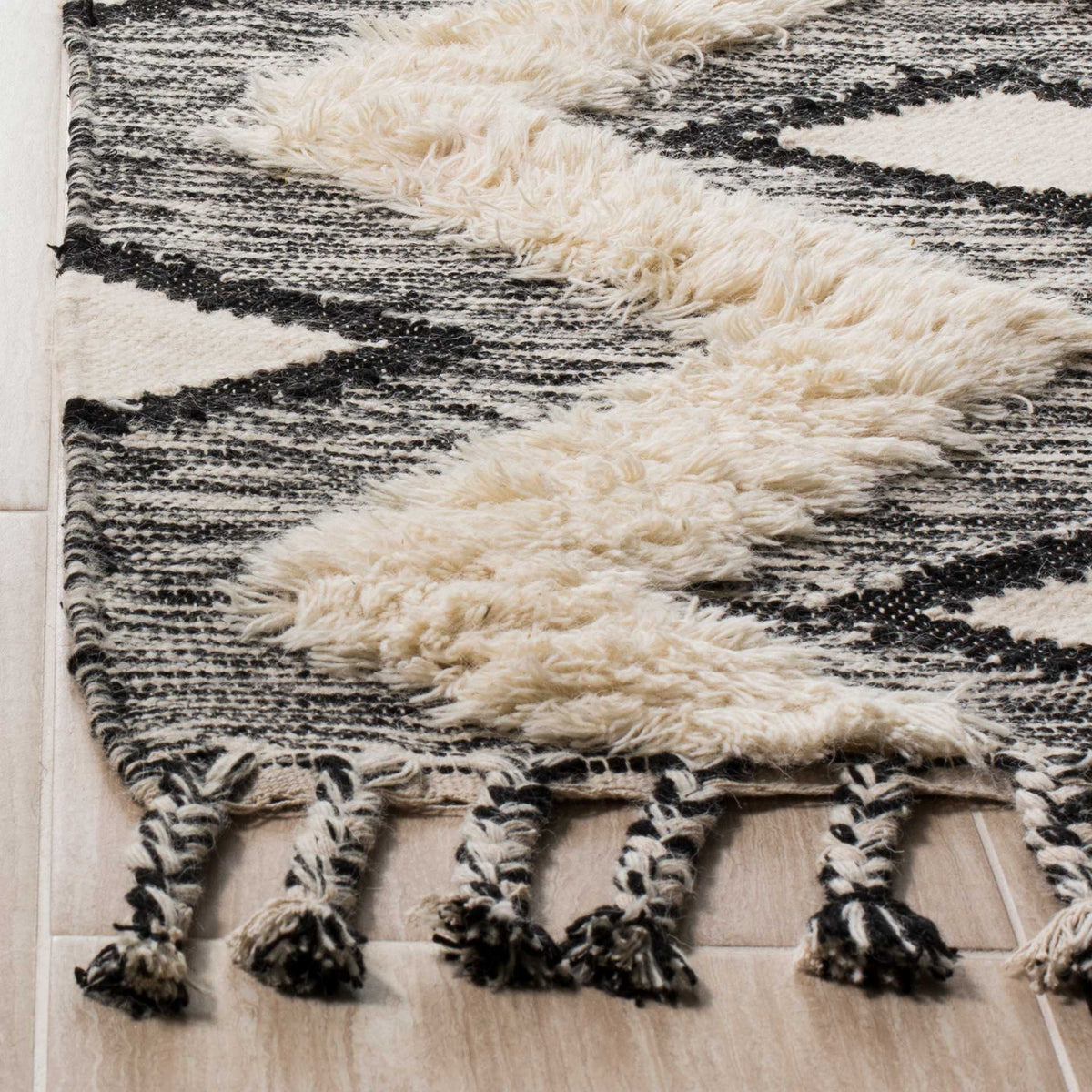 Raised ivory tufts contrast with flat black-and-ivory weaving and twisted fringe.