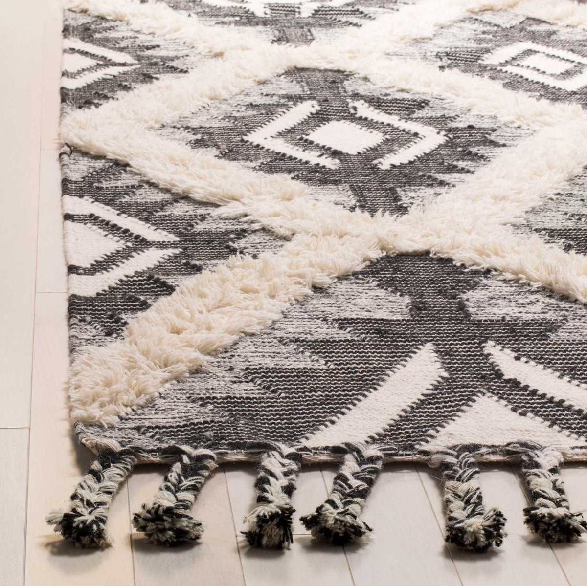 Raised ivory pile contrasts with dark woven motifs and braided fringe