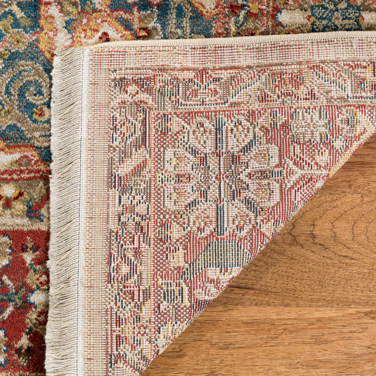 A finely woven backing carries the floral design beneath the rug's colorful pile and ivory fringe