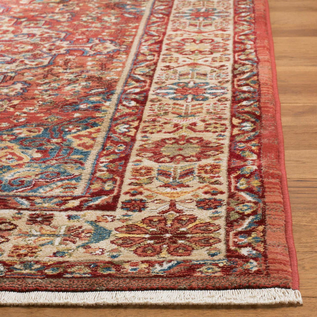 An ivory floral border and short fringe soften the vivid red rug with blue and gold accents