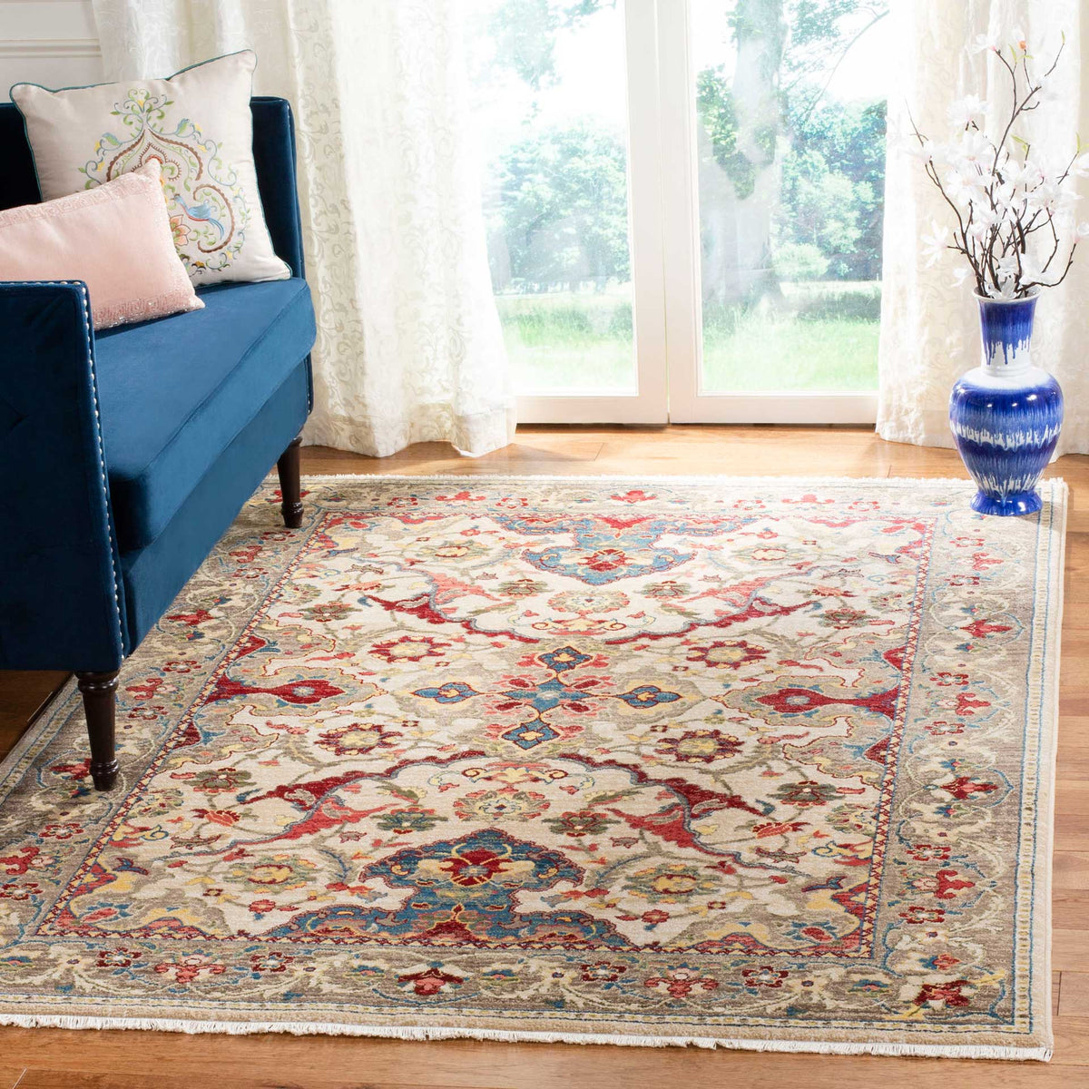 An ivory and taupe floral rug brings red and blue accents and an ornate border to the living room.