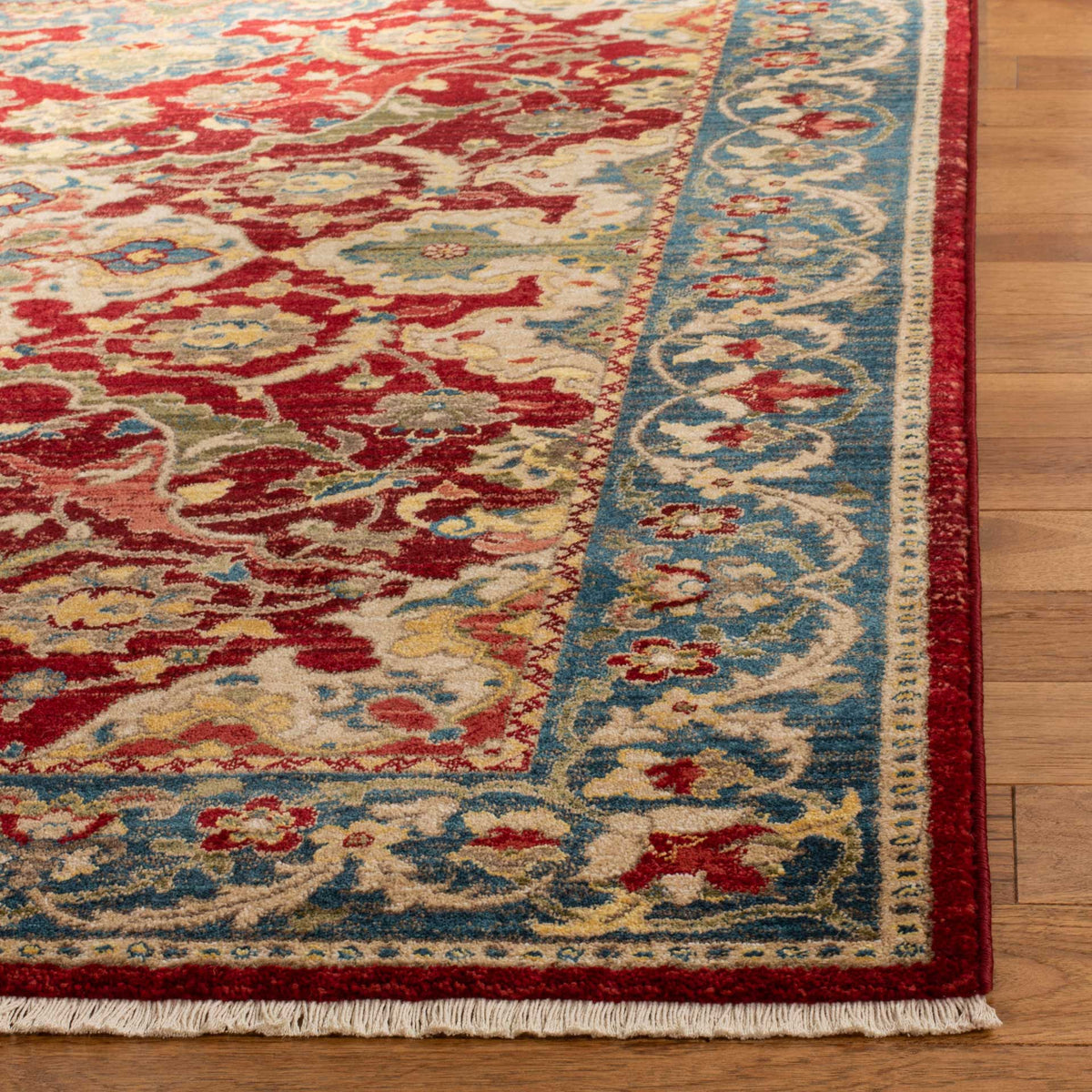 A blue floral border frames the red field, finished with a crimson edge and ivory fringe.