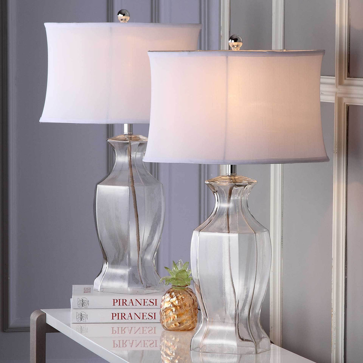 Two clear glass table lamps cast a warm glow through their white fabric shades