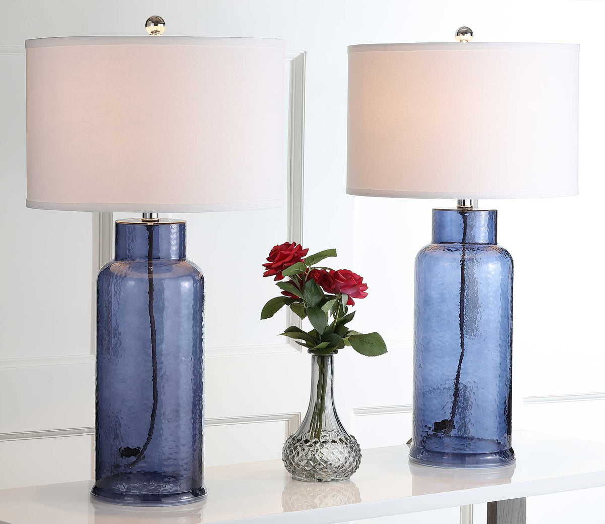 Two blue glass bottle lamps cast a warm glow through their white drum shades