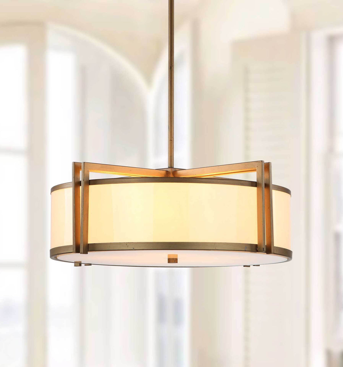 Warm light shines through the cream drum shade beneath sculptural antique gold arches