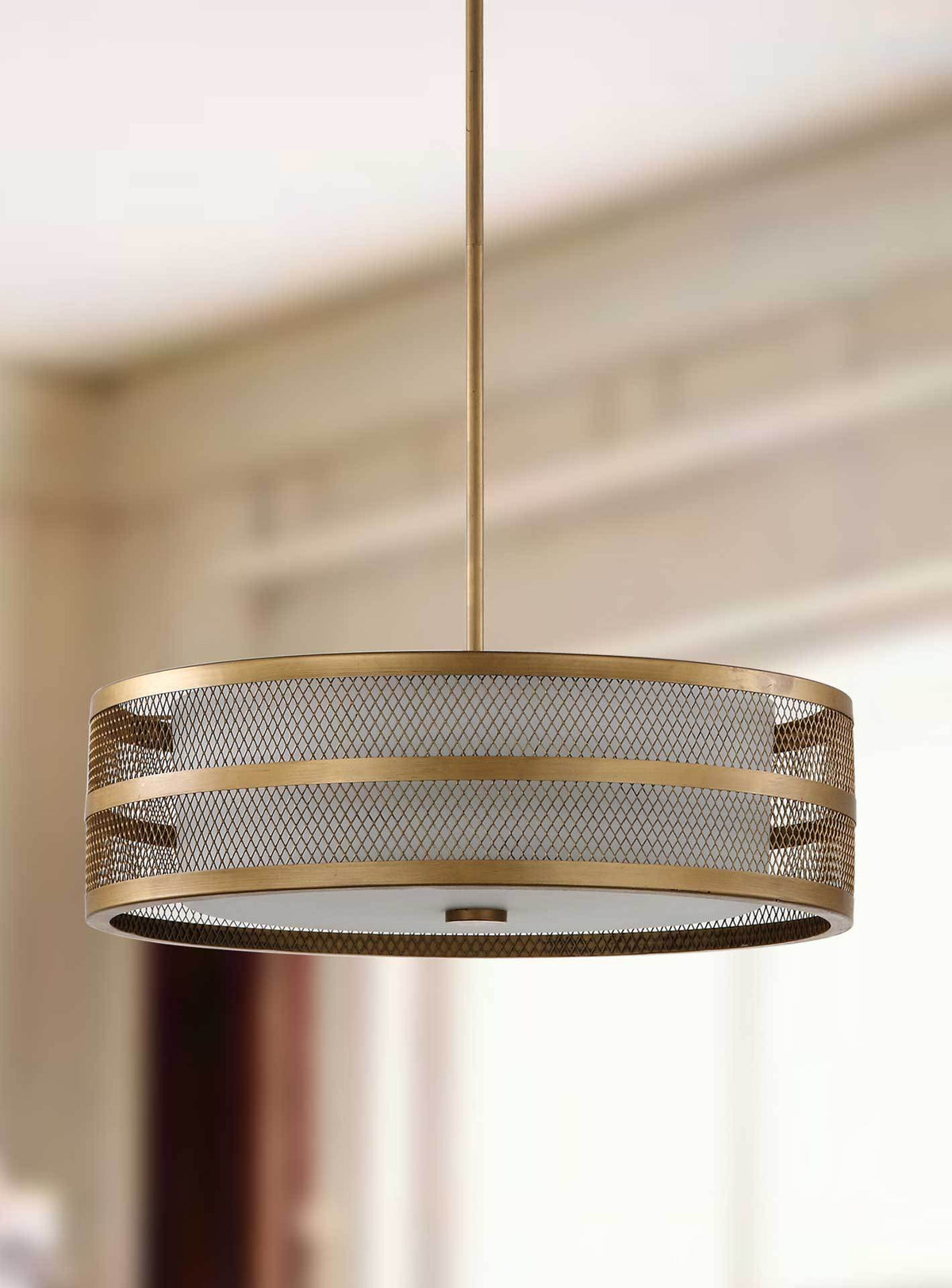 A perforated gold drum and white glass diffuser lend this pendant subtle texture.