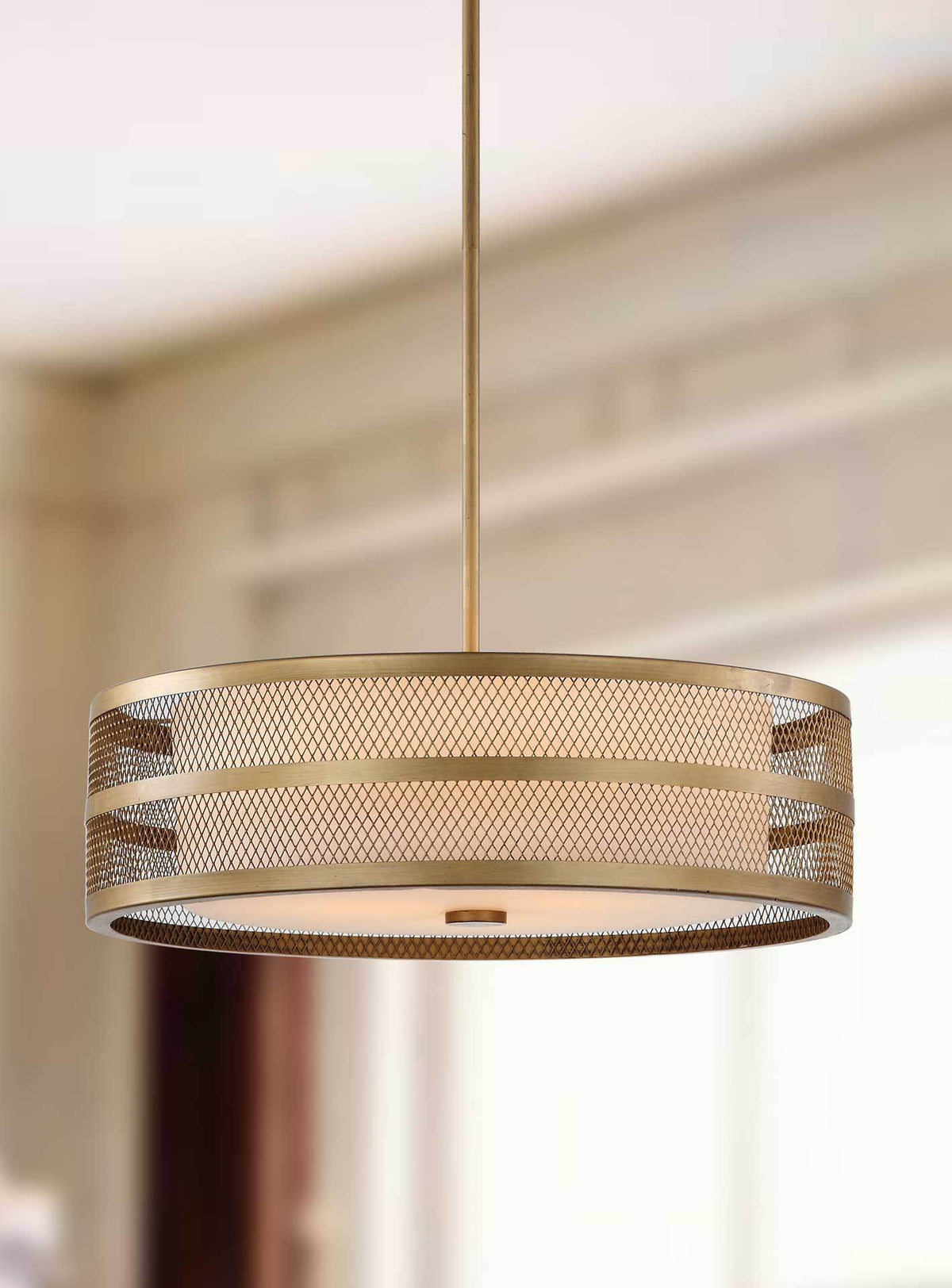 An antique gold mesh drum glows warmly around a white glass shade.