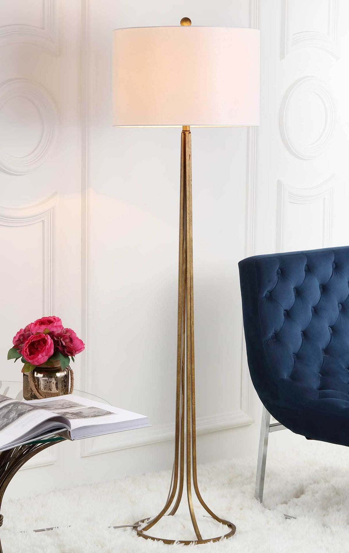A warm glow shines through the off-white drum shade above the lamp's airy bronze frame