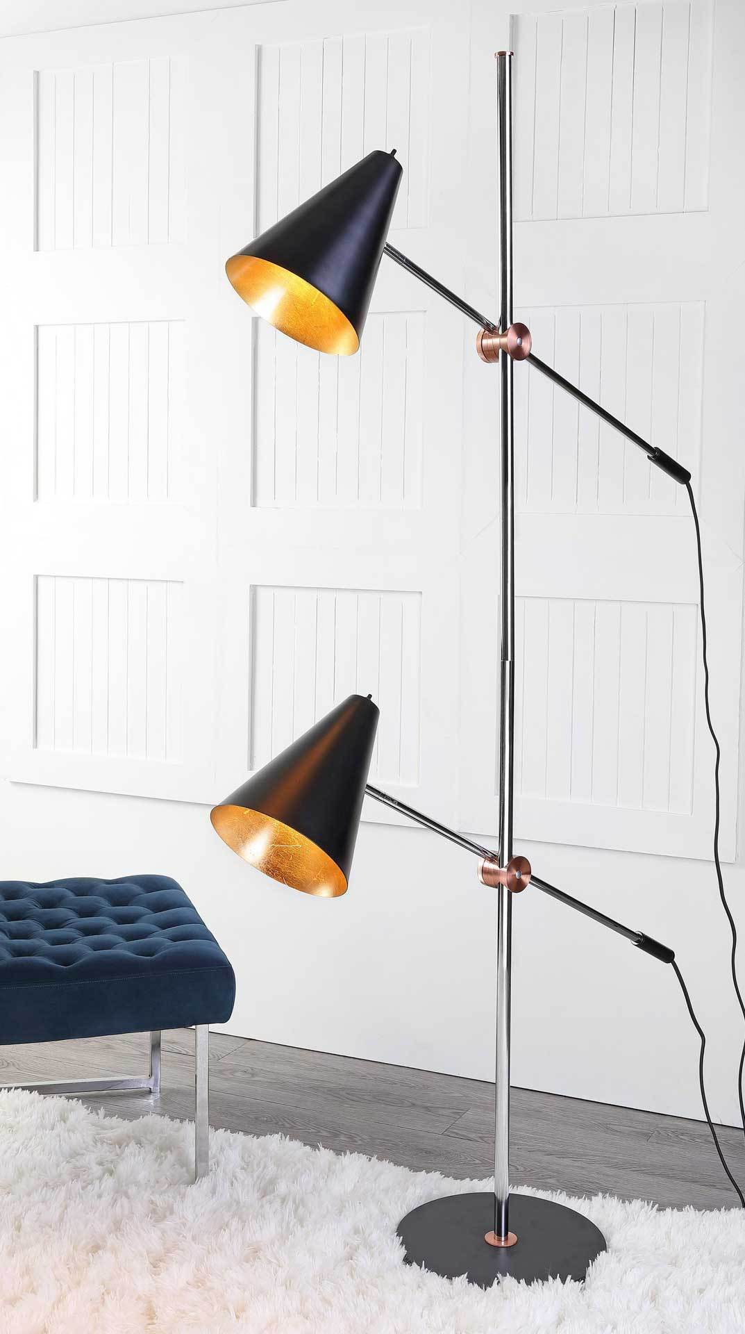 Two gold-lined black shades cast a warm glow from a slim chrome floor lamp