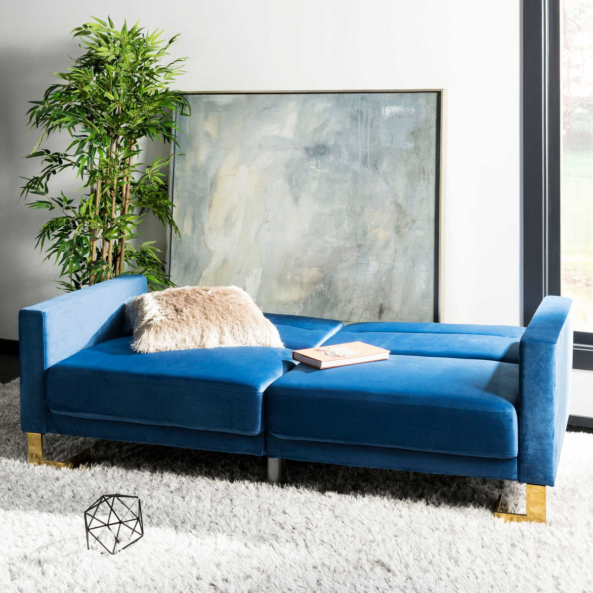 Navy velvet cushions unfold into a spacious sleep surface with squared arms at each end.