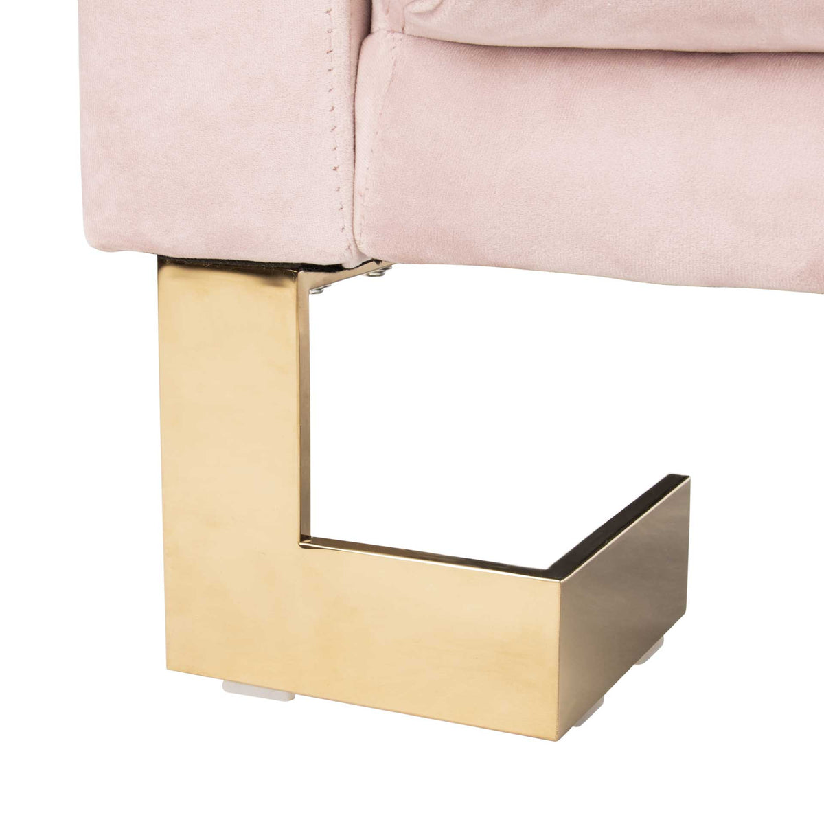 A sculptural brass-tone metal foot adds a geometric accent beneath plush blush upholstery.