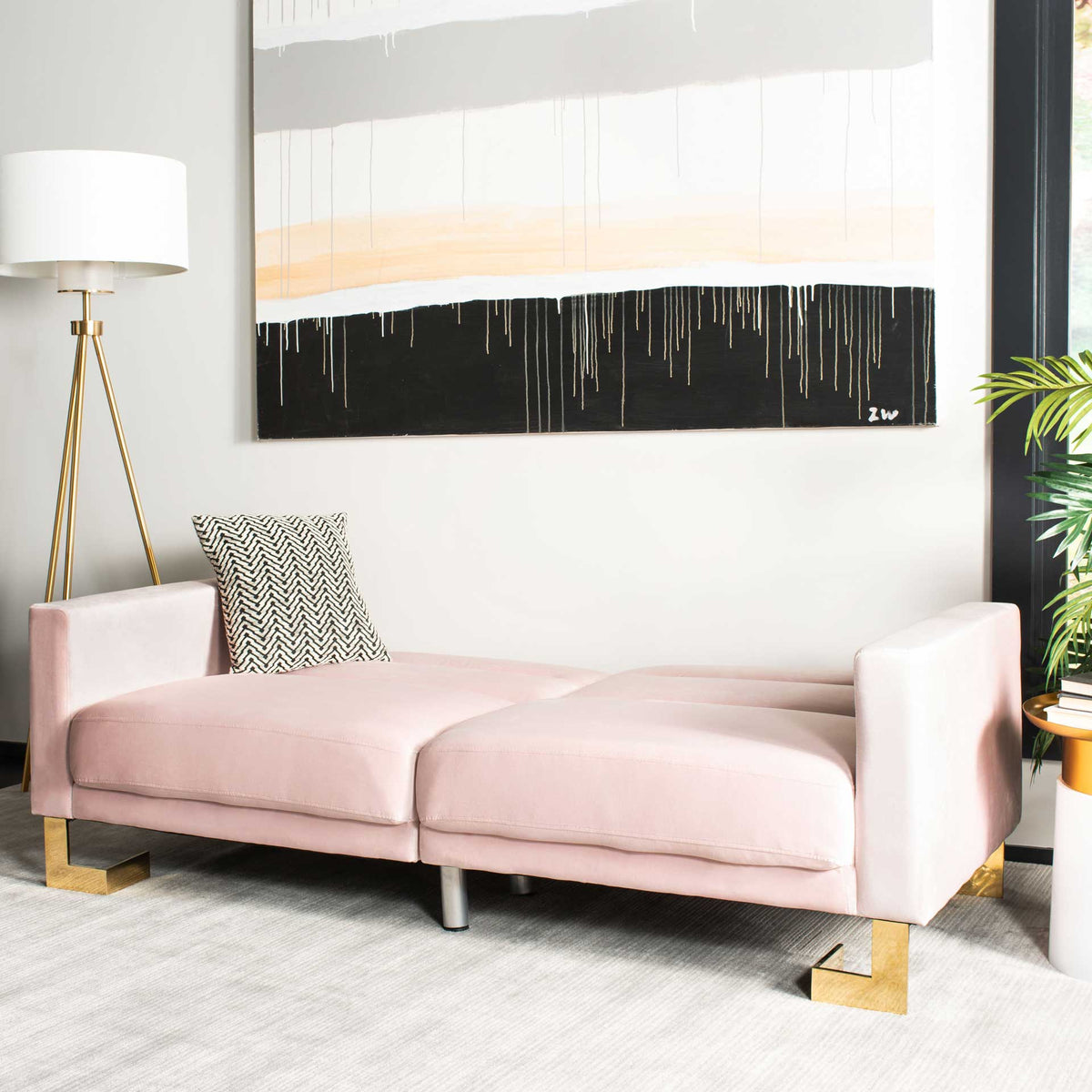 Blush velvet cushions unfold into a roomy sleep surface bordered by clean-lined arms.