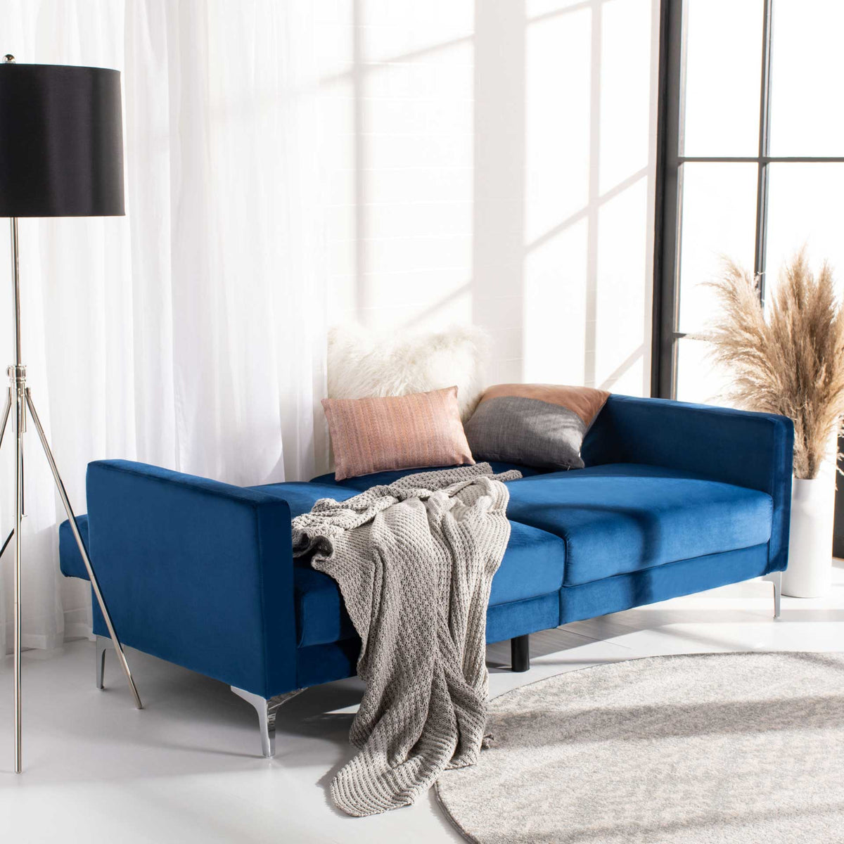 Navy velvet futon unfolds into a spacious lounge bed while squared arms stay supportive