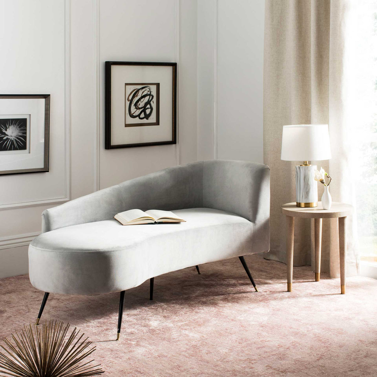 A gray velvet settee adds plush, sculptural curves and delicate metal legs to a living room