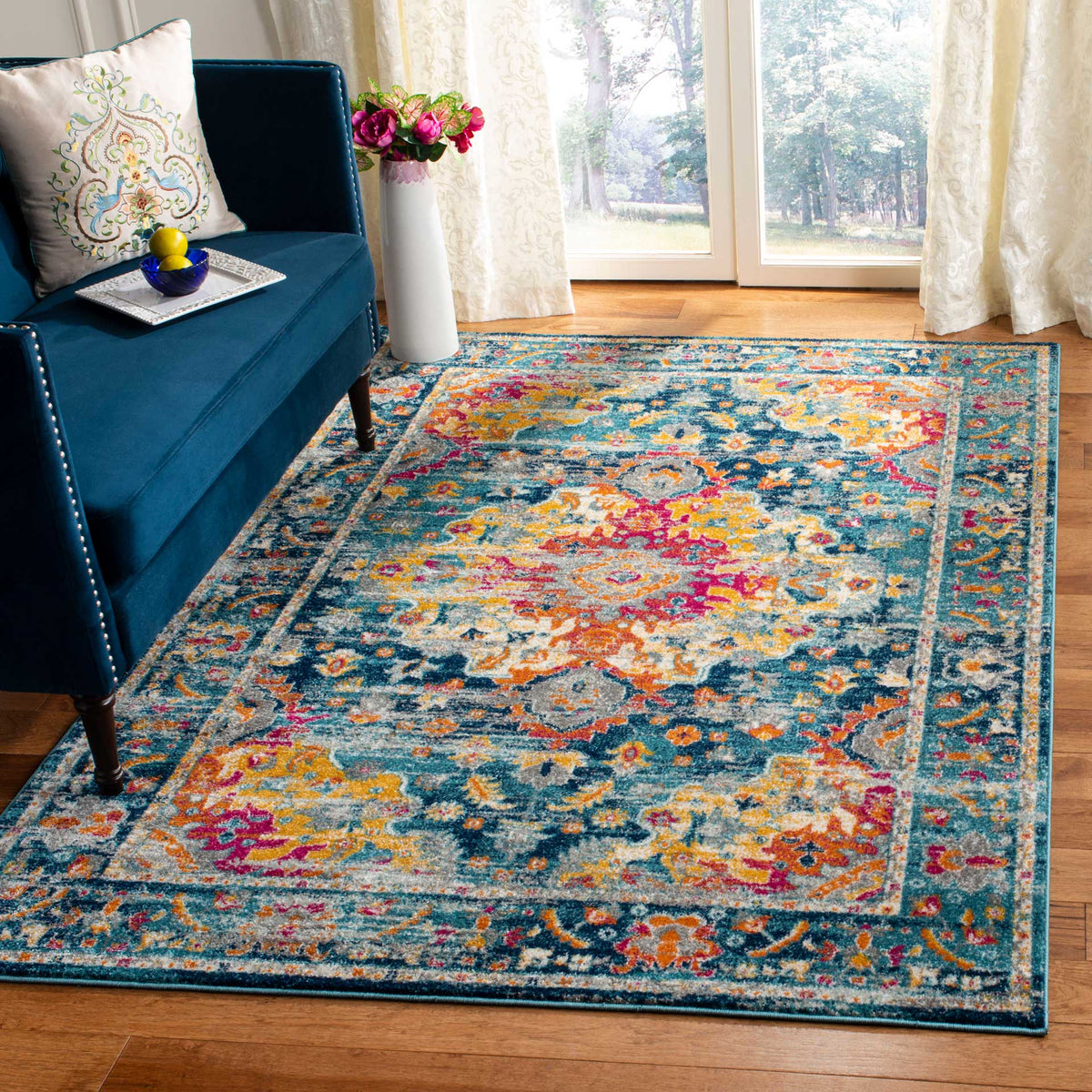 Teal and fuchsia floral rug anchors a bright living room beside a deep blue sofa