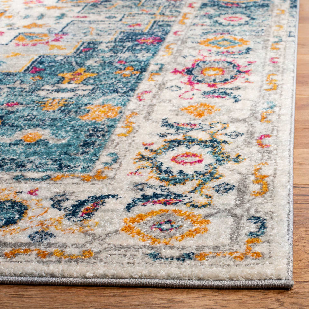 Bound rug corner with a textured pile and colorful floral motifs along the ivory border