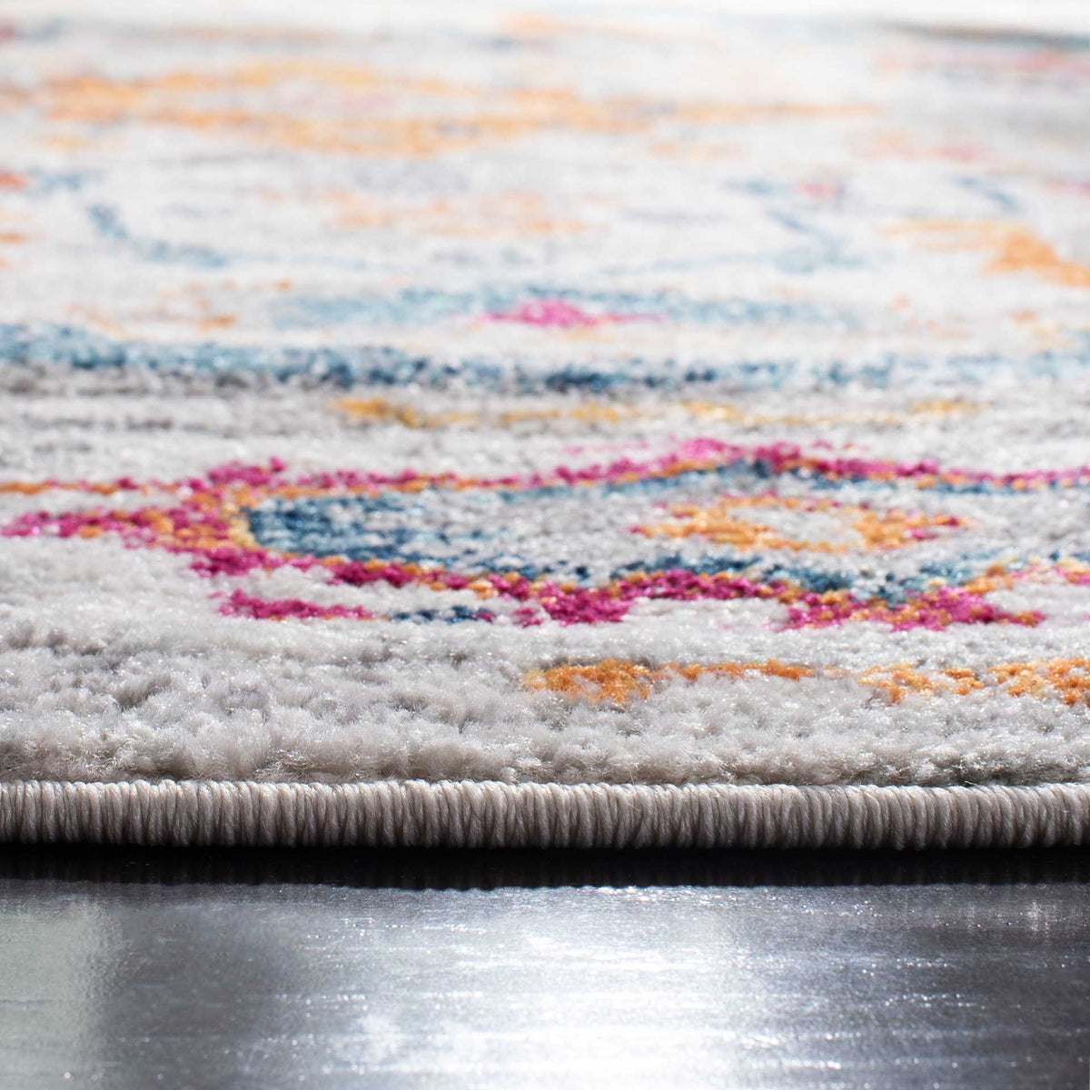 Textured pile reveals vivid pink and turquoise motifs beside a neatly bound edge