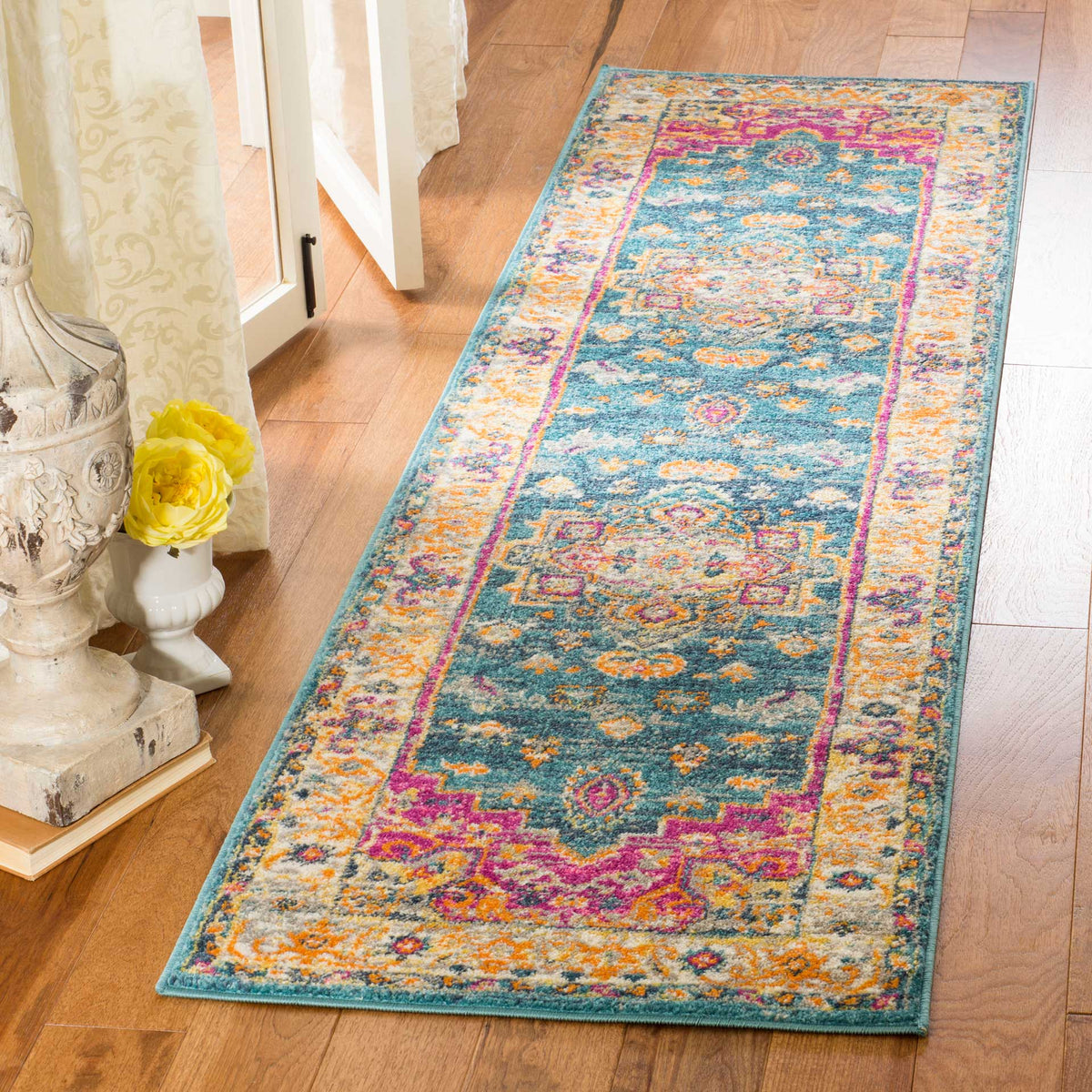 Traditional blue runner rug with vivid pink and orange accents brightens a wood-floored space