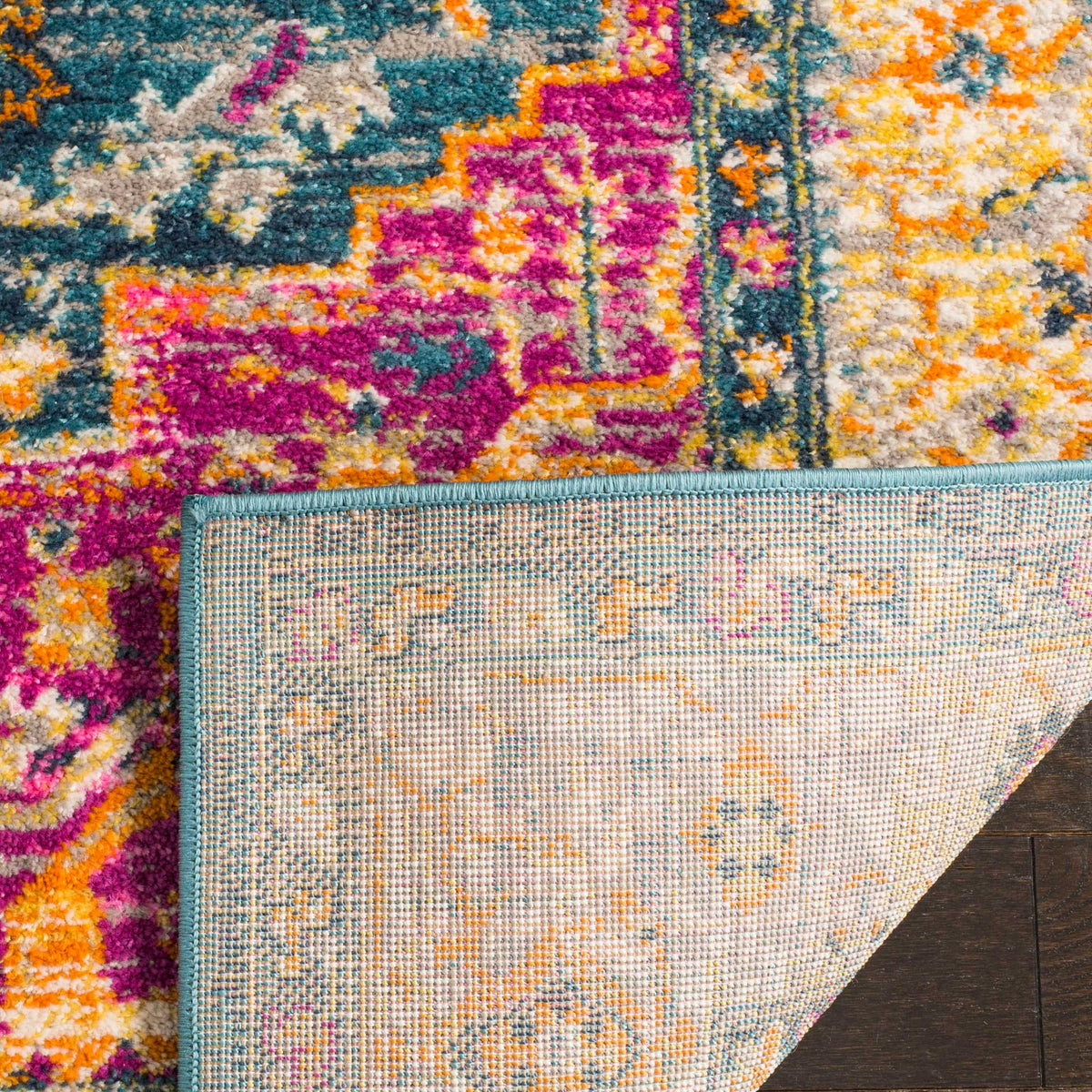 A folded edge reveals woven backing beneath the rug's colorful pattern and blue binding