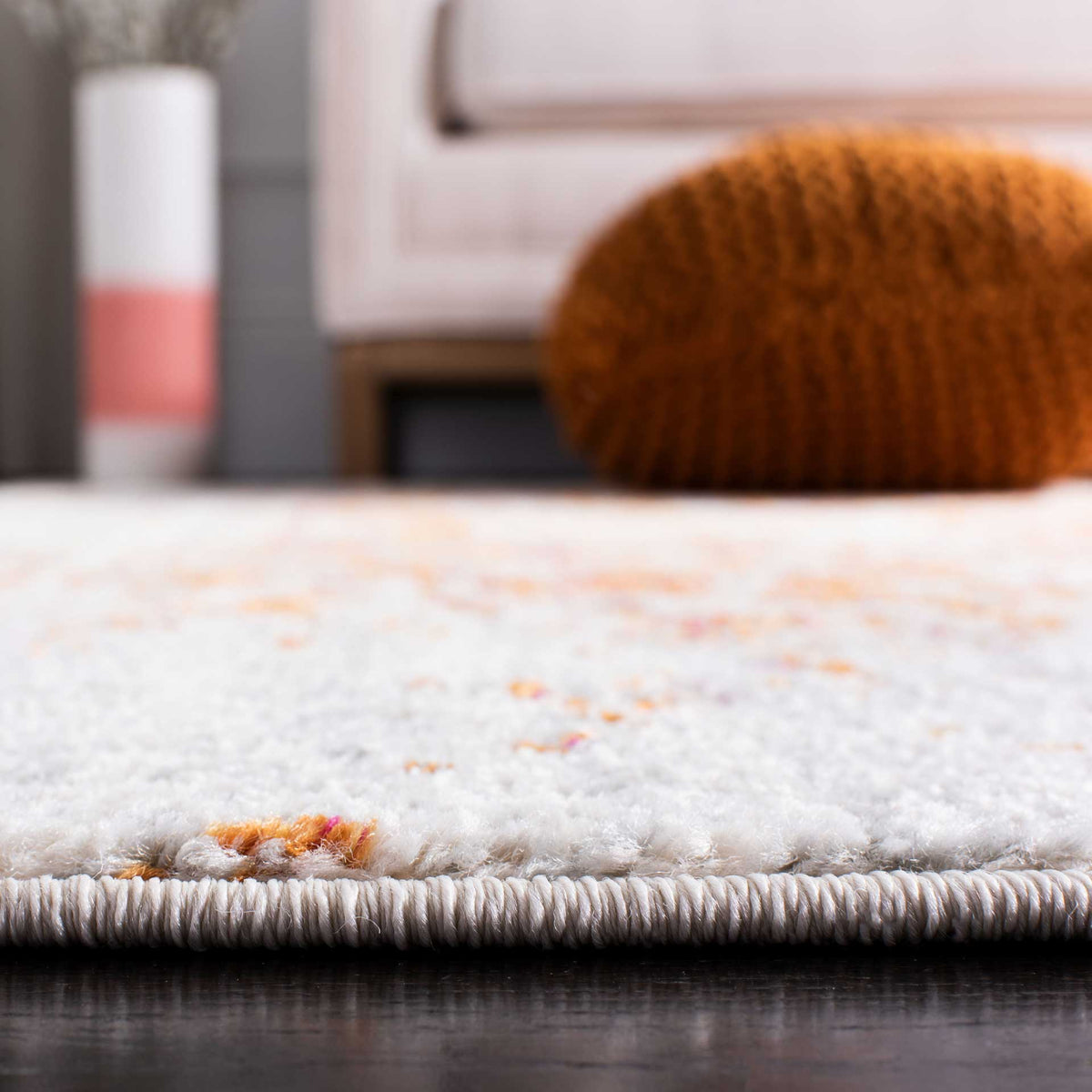 Plush ivory pile with subtle orange accents meets a neatly finished rug edge