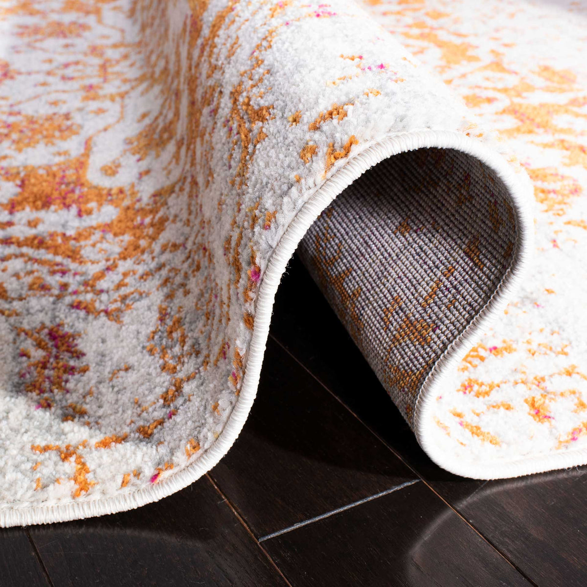 A folded orange and ivory rug reveals woven backing and a neatly bound edge