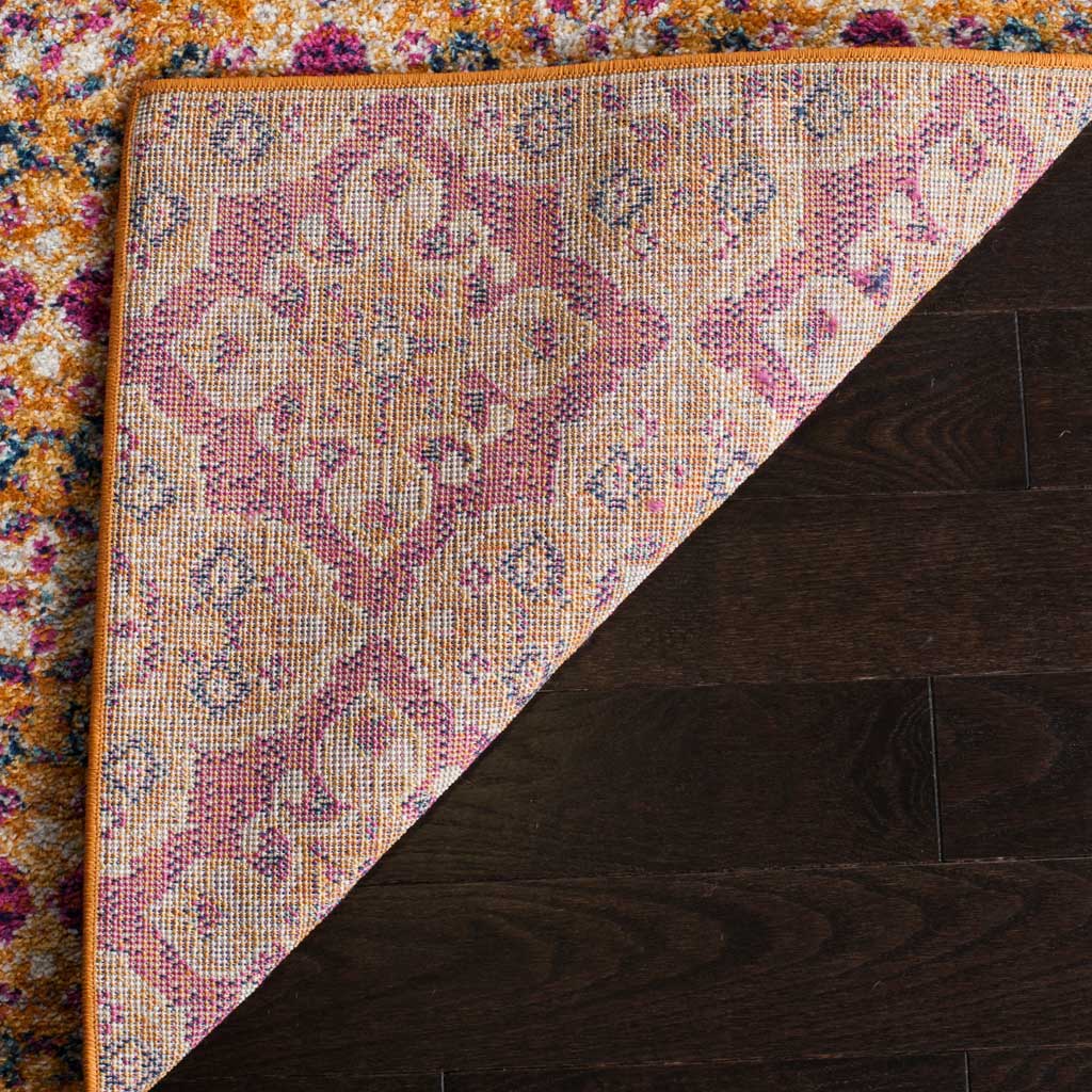 A folded rug edge reveals patterned woven backing beneath the bright fuchsia and gold pile