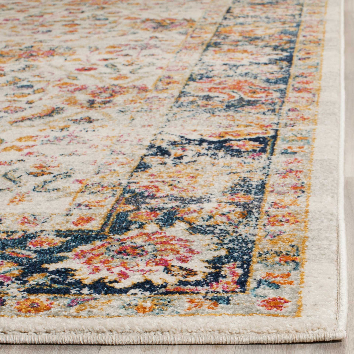 A neatly bound edge finishes the cream and navy floral rug with bright pink and orange accents.