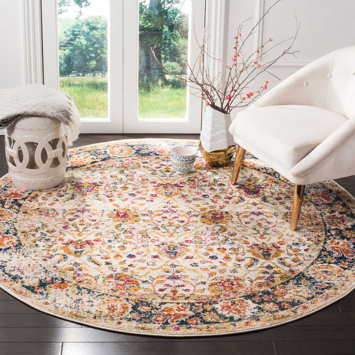 Round cream rug with colorful floral motifs brightens a seating area beside a white chair