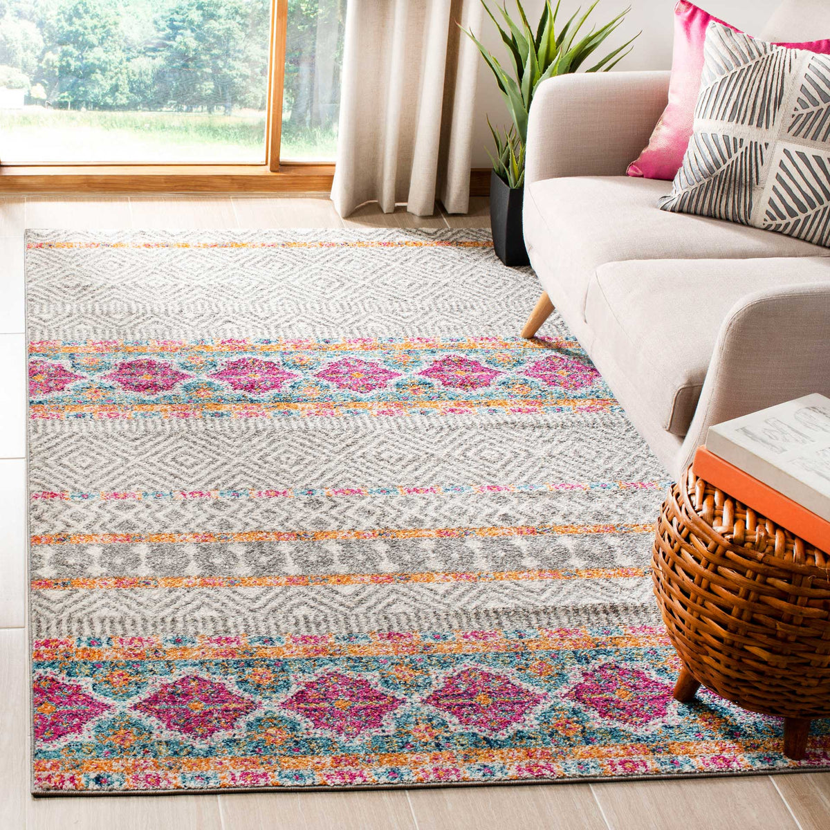 Bands of pink and teal medallions enliven this gray and ivory rug beside a cream sofa.