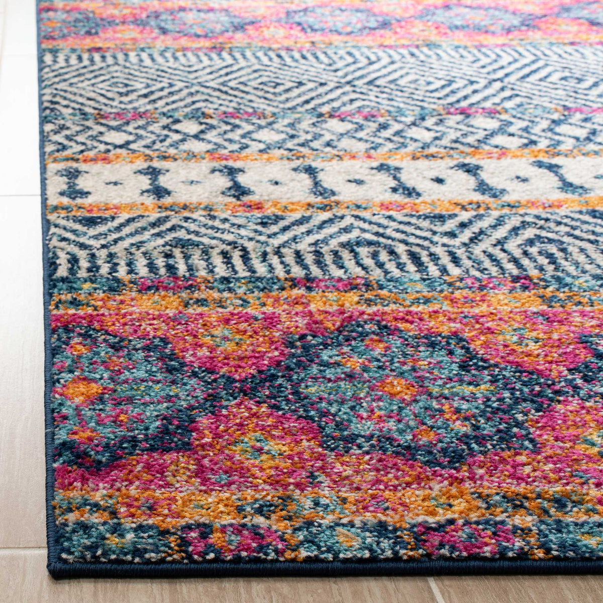 Vibrant pink and orange medallions brighten textured navy and ivory pile above a neatly bound edge.