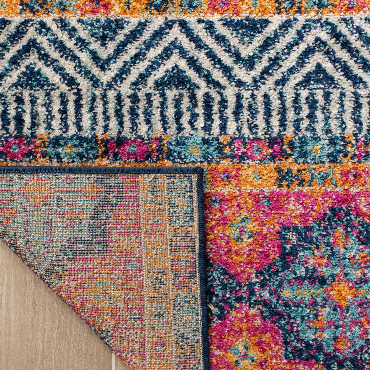 A folded edge reveals woven backing beneath navy diamonds and bright multicolor medallions.