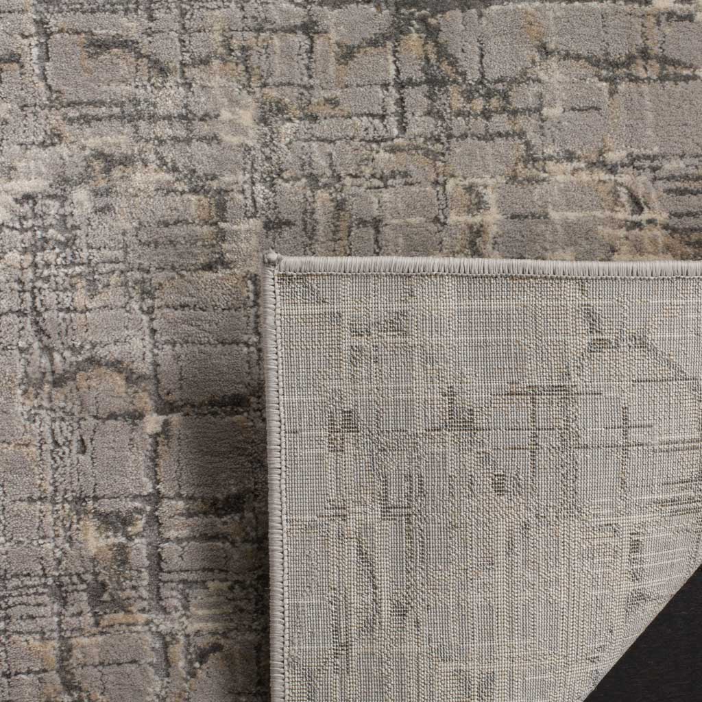 A tightly woven backing underlies the rug's textured gray pile and distressed pattern