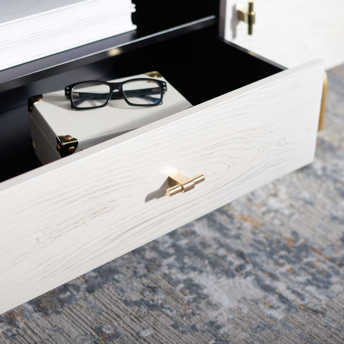 An open whitewashed drawer offers tidy storage for small essentials beneath the dark shelf.