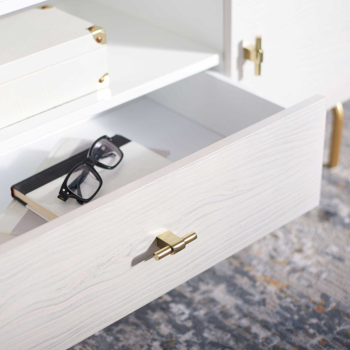An open whitewashed drawer reveals handy space for media accessories beneath the central shelf.