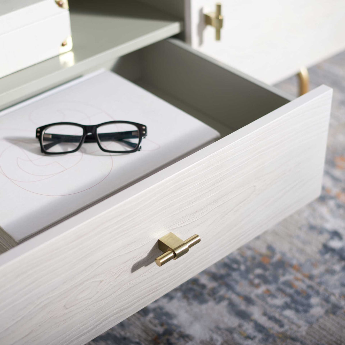 An open drawer offers tucked-away storage below the gray media shelf, finished with a gold-tone pull.