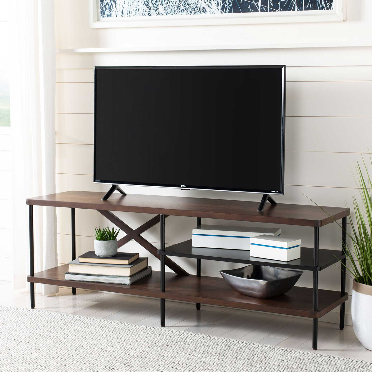 Walnut and black TV stand holds a large screen above open shelves for books and decorative accents