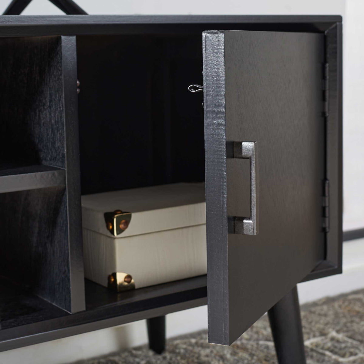 The black cabinet door opens to tucked-away storage for media accessories.