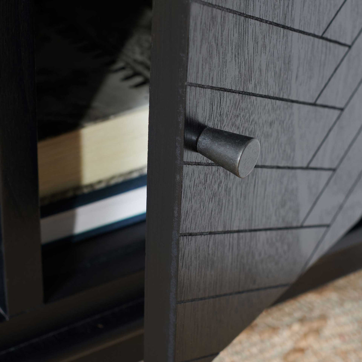 A dark metal knob accents the herringbone-patterned cabinet door beside the open shelves.