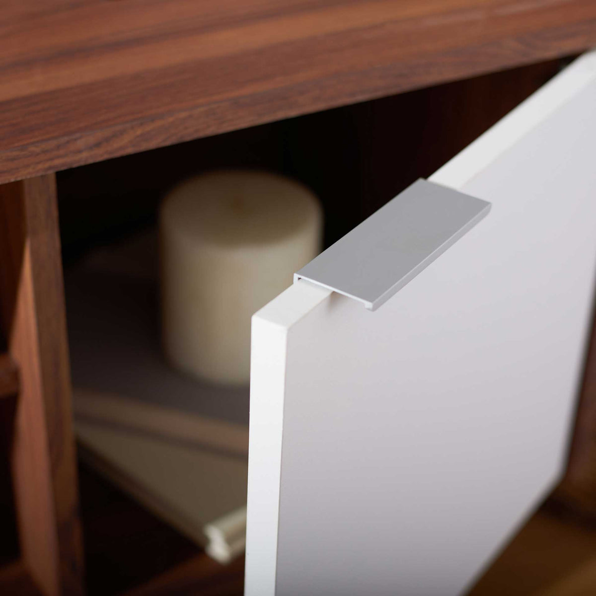 Silver pull accents an open white cabinet door, with storage visible behind it