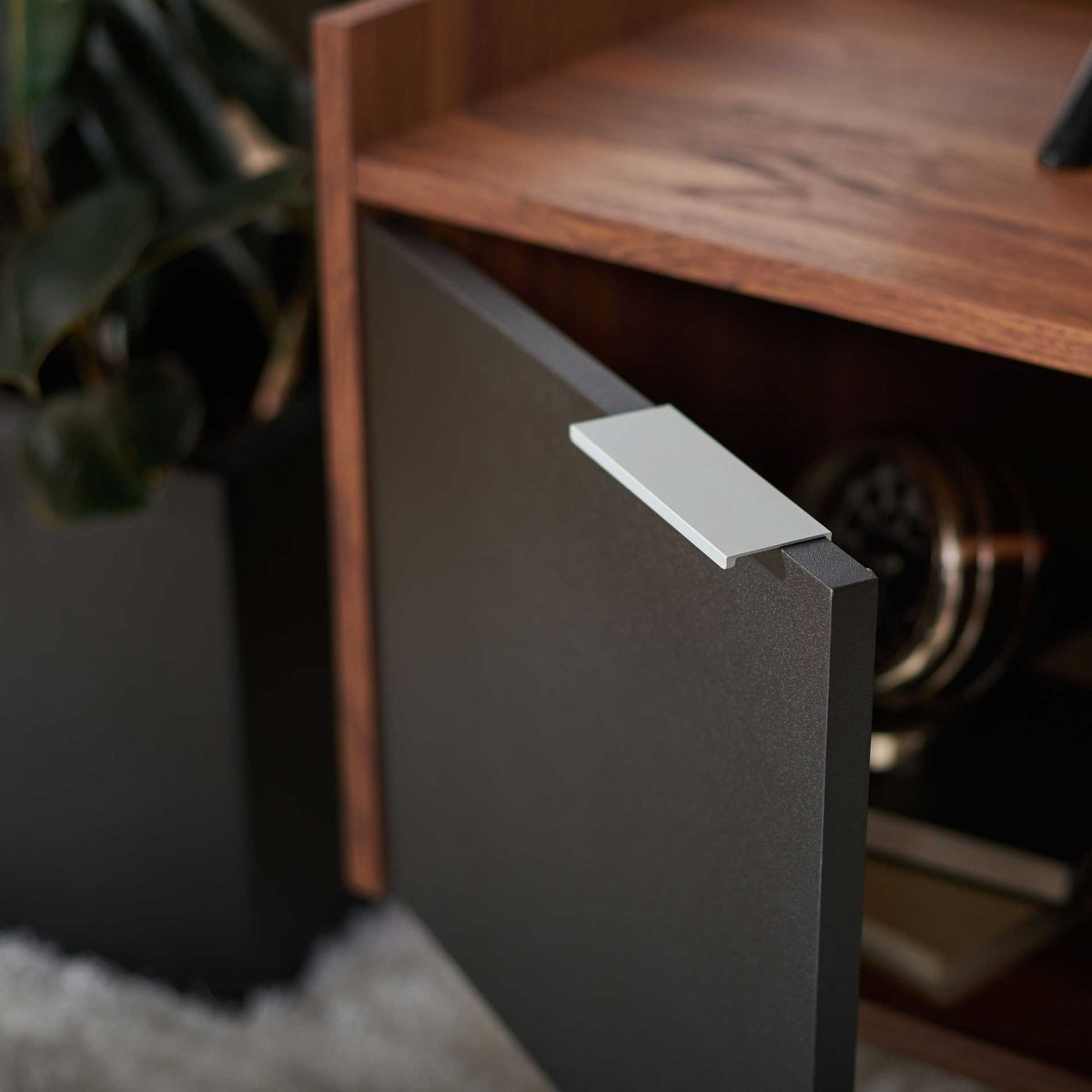 Silver pull accents an open black cabinet door, with storage visible behind it