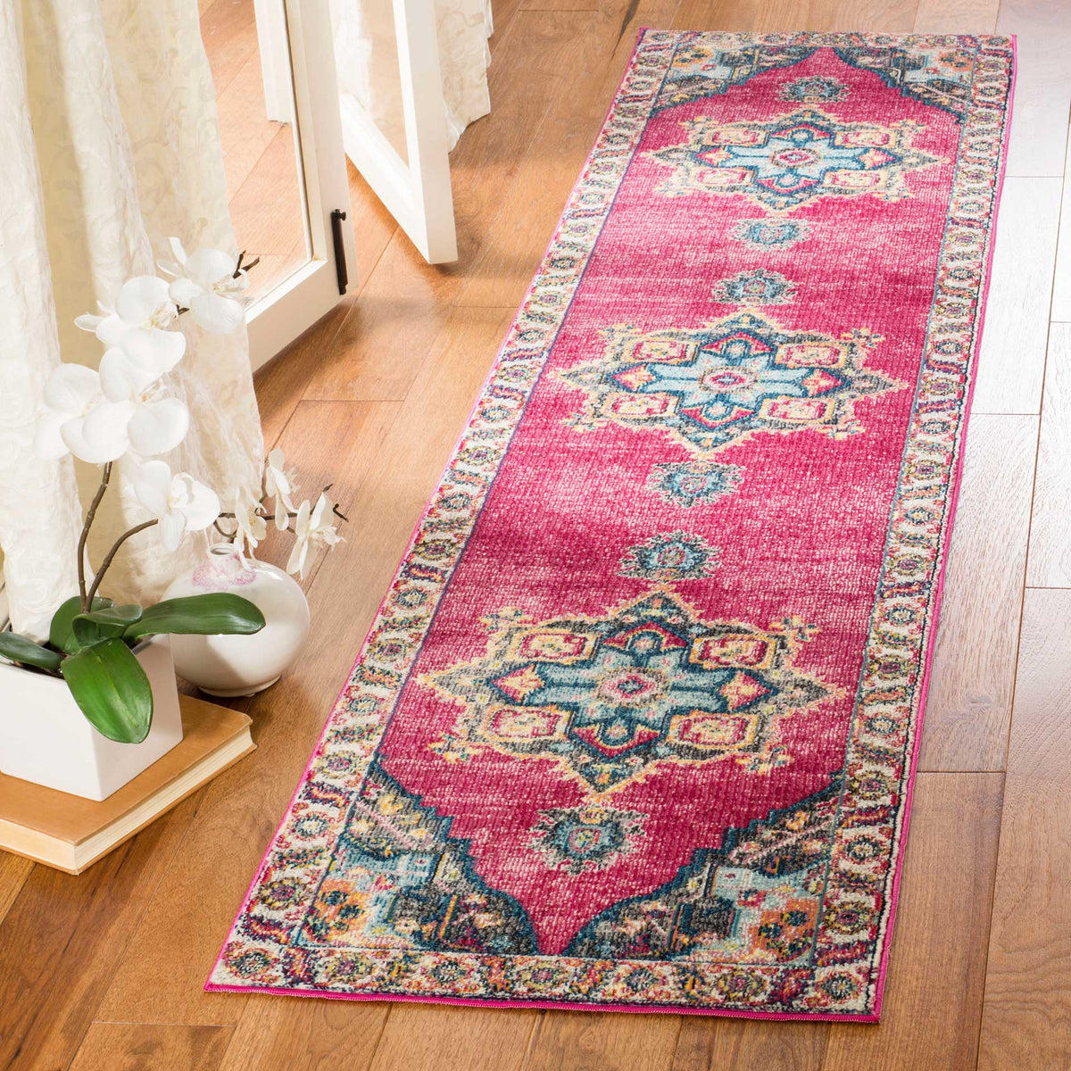 Vivid fuchsia runner with intricate multicolor motifs brightens a wood-floored entryway