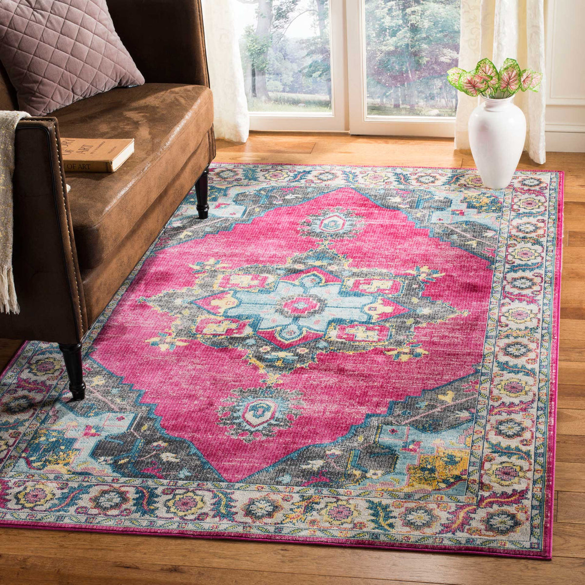 Vivid fuchsia medallion rug adds bold color beside a brown sofa, with teal accents and ornate floral trim