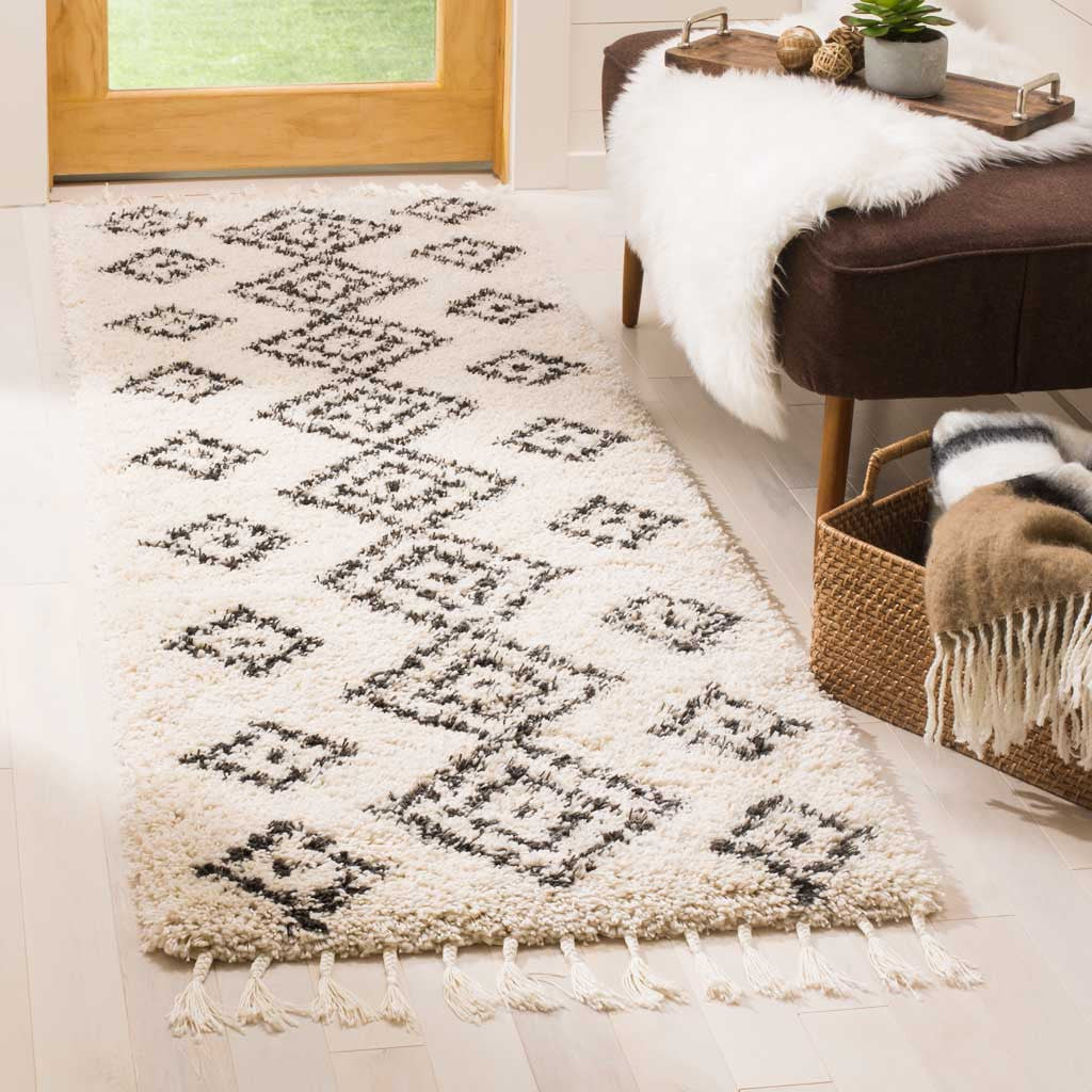 Plush cream runner with charcoal diamonds and tassels adds softness beside an upholstered bench