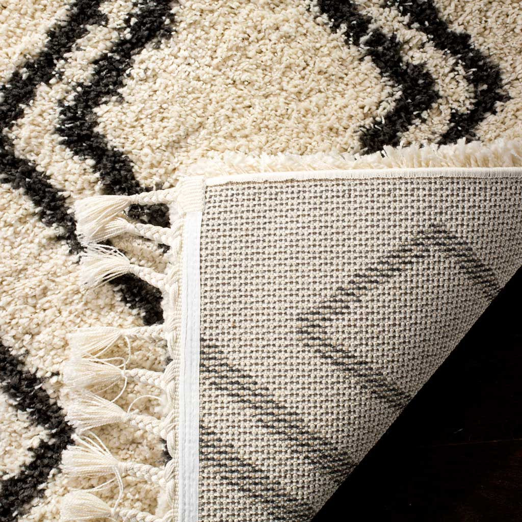 Woven backing meets plush cream-and-charcoal pile and braided fringe