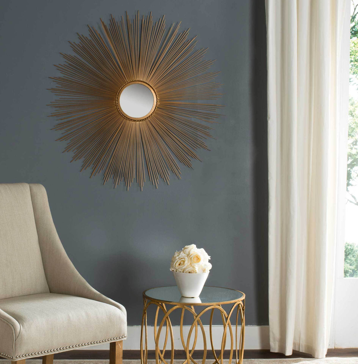 A gold sunburst mirror adds warm metallic texture to a charcoal wall