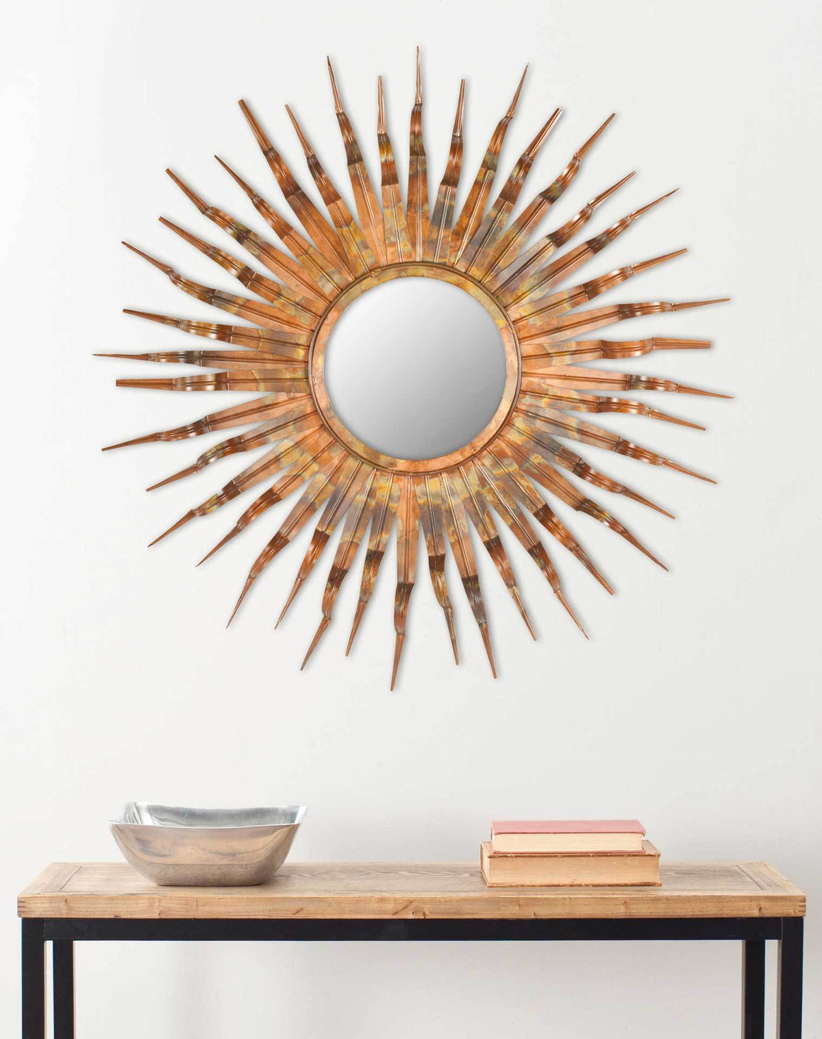 A copper sunburst mirror brightens the wall above a wood and metal console