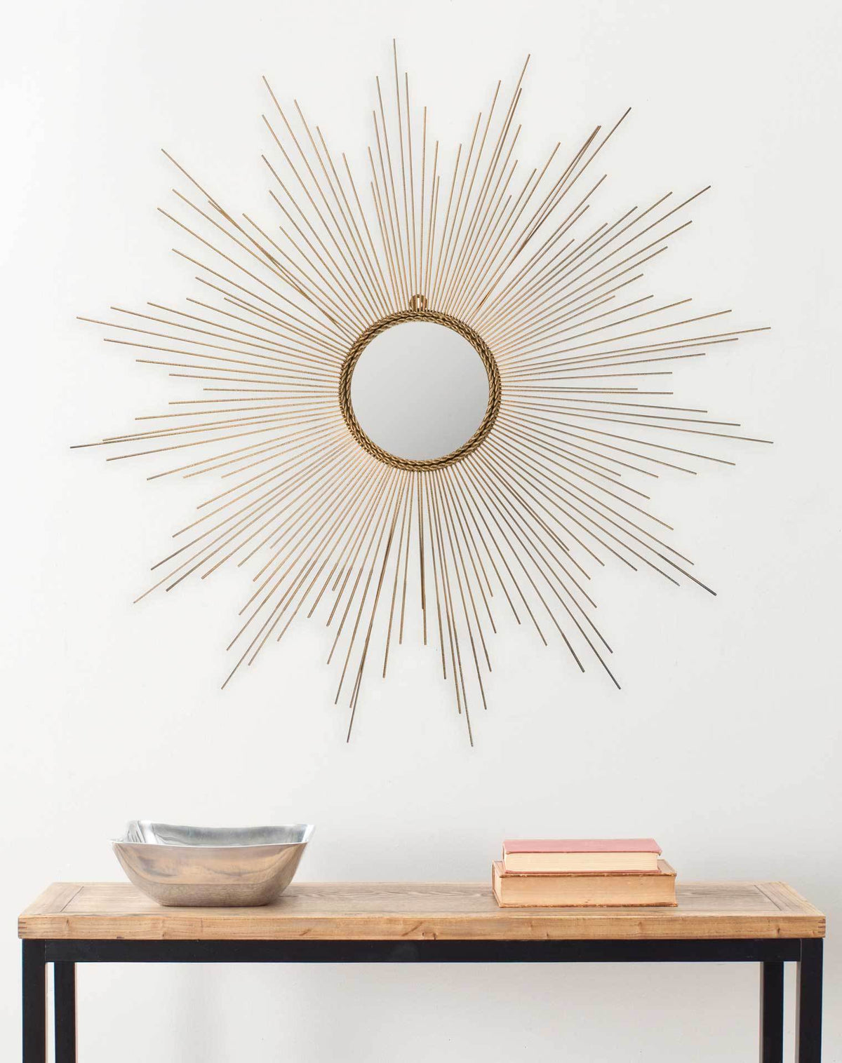 A round mirror with delicate golden rays brings warmth and character to a wall